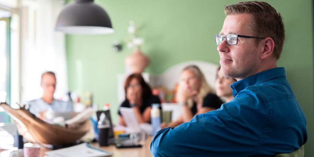Manna Leendert de Jong Trainer op de voorgrond, deelnemers op de achtergrond met diepteperspectief